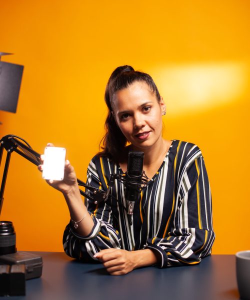 Content creator holding mini led and talking about during podcast. Video blogger recording a vlog with technology product equipment use in videography and photography